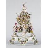 Reloj de sobremesa de porcelana esmaltada con decoración tipo floral y figuras escultóricas de