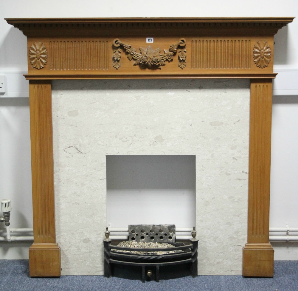 A pine fire surround with carved floral appliqué & fluted frieze, & fluted supports, 50” wide x 46¾"