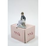 A Lladro Nao porcelain ornament in the form of a young girl seated on a log with three rabbits by