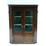 A late 18th century inlaid mahogany hanging corner cupboard enclosed by pair of bevelled glass panel