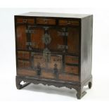 A Chinese-style wooden cabinet with cupboard to centre enclosed by pair of panel doors above a