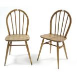 A pair of Ercol spindle-back dining chairs with hard seats & on round tapered legs with spindle