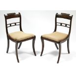 A pair of regency mahogany dining chairs with carved anthemions to the bow backs, having padded