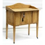 A small pine washstand enclosed by centre panel door, & on short square tapered legs with brass