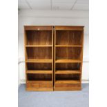 A pair of teak tall standing bookcases, each fitted three open shelves above two small drawers, & on