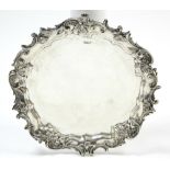 A LATE VICTORIAN CIRCULAR SALVER, the wide raised & shaped border with rococo leaf-scroll