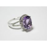 AN AMETHYST RING, the oval cut stone approx. 5.8 carats, set with in a border of small diamonds to a