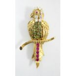 A YELLOW METAL & GEM-SET BROOCH modelled as a parrot perched upright on a branch, its head & neck