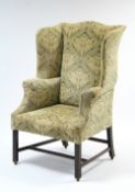 A late 18th century style upholstered wing-back armchair on mahogany square chamfered legs with H-