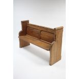 A pine pew with panelled back, hard seat & with shaped end supports, 55½" long x 35" high.