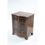 A reproduction mahogany crossbanded small serpentine-front chest fitted two short & two long