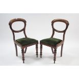 A pair of Victorian carved walnut balloon-back dining chairs with padded drop-in seats & on turned