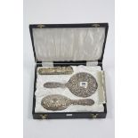 A silver-backed three-piece dressing table set comprising a hand mirror, hair brush & clothes brush,