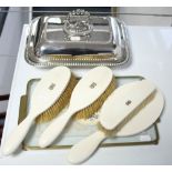 A silver plated entrée dish; a four-piece ivory dressing table set; & a glass tray inset lace