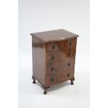 A reproduction mahogany serpentine-front bedside chest fitted four long graduated drawers with brass