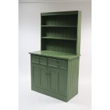 A green painted pine dresser with two open shelves to the panelled back, the base fitted two