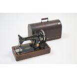 A Singer hand sewing machine with oak case.