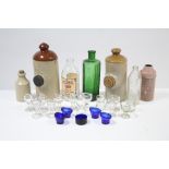 Thirteen clear glass eye wash cups; four blue tinted glass ditto; two stoneware foot warmers; & four