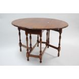 A walnut oval gate-leg dining table on baluster-turned legs with plain stretchers, 36” x 46½”.