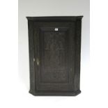 A carved oak hanging corner cupboard enclosed panel door; 26" wide x 37" high (replaced hardboard