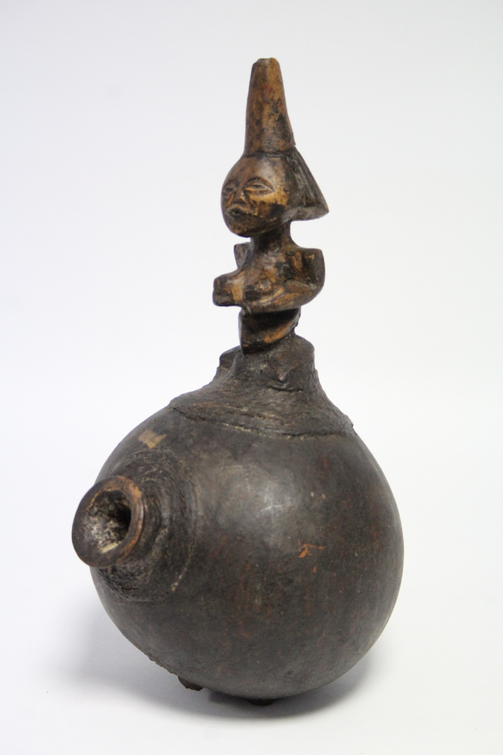 An African smoking pipe with short bowl to the round gourd body, with carved figural handle,