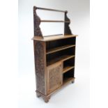 A late Victorian carved oak standing open bookcase with carved panel door below, & two open