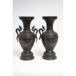 A pair of Chinese bronze ovoid vases with dragon side handles decorated with birds & shrubs on a