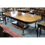 An early 20th century mahogany extending dining table with rounded ends, two additional leaves, & on