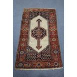 A Persian rug with cream ground centre with arrow-head medallion, within wide crimson floral border;