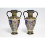 A pair of Doulton Lambeth stoneware two-handled vases, the slender ovoid bodies decorated with