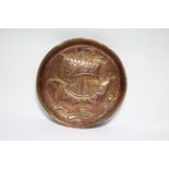 A NEWLYN COPPER SHALLOW DISH by JOHN PEARSON, embossed with a Celtic sailing ship, with fish