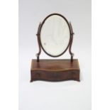 A George III mahogany oval bevelled swing toilet glass on serpentine-front base fitted three small