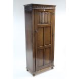 An oak hall cupboard by Fleet Furniture Co. enclosed by linen-fold & panel door & on ball feet, 29½”