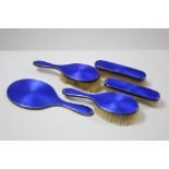 A George V silver and blue enamelled backed five-piece dressing table set comprising of a hand