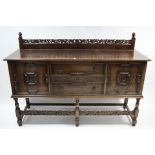 An early 20th century oak sideboard with pierced & carved stage back, fitted two long drawers to