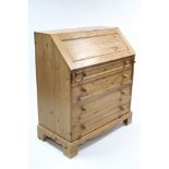 A pine bureau with fitted interior enclosed by fall-front above four long graduated drawers with