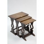 A reproduction oak nest of three rectangular occasional tables, each table on pierced & shaped end