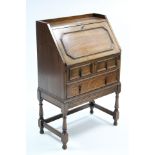 A 1930’s small oak tray-top bureau with fitted interior enclosed by fall-front above two long