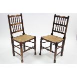 A pair of Lancashire-style spindle-back dining chairs with woven string seats & on turned legs