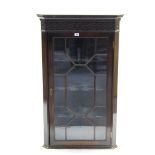 A mahogany hanging corner cabinet with blind fretwork frieze, & fitted three shaped shelves enclosed