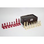 A late 19th/early 20th century carved bone chess set of natural & red stain (size of Kings 2¾”