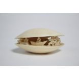 A Chinese ivory clam-shell netsuke with carved & pierced figure & tree design to centre, 1¾” wide.