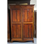 An early 20th century mahogany wardrobe with dentil cornice, fitted interior enclosed by pair of