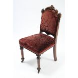 A late Victorian carved walnut frame occasional chair with padded back and sprung seat upholstered