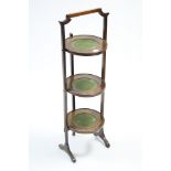 An Edwardian inlaid-oak folding cake stand of three circular tiers, & on square supports, 36”