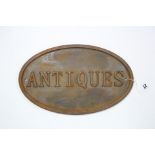 A modern cast-iron oval sign “ANTIQUES”, 8¼” x 13½”.