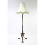 An Edwardian oxidised brass standard lamp with vase-shaped centre column & on three stylised legs,