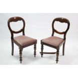 A pair of Victorian mahogany balloon-back dining chairs with padded drop-in seats, & on turned