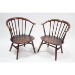 A pair of Ercol small elbow chairs with spindles to the rounded backs, hard seats, & on tapered legs