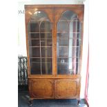 A Queen Anne-style burr walnut tall display cabinet with four adjustable shelves enclosed by pair of